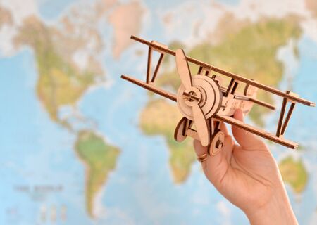 close up photo of woman's hand holding toy airplane against map of world. empty space you can place your text or information.の写真素材