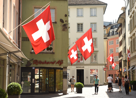 Zurich, Switzerland - June 03, 2017: People on the street of Zurich decorated with flags of Switzerland. Swiss Flags on the facade building in historic city center of Zurich, Switzerland.のeditorial素材