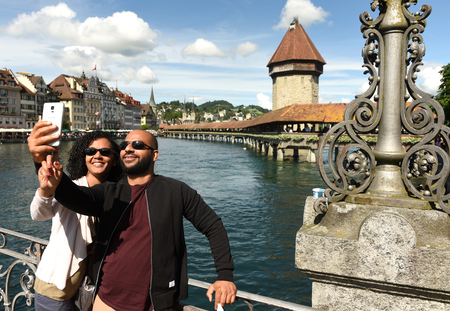 Lucerne, Switzerland - June 04, 2017: Couple makes selfie at the embankment lake Lucerne with Chapel Bridge (Kapellbrucke) and Water Tower at the background, Switzerland.のeditorial素材