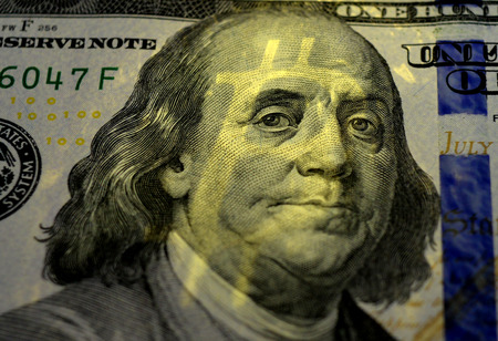The shadow of Bitcoin on Benjamin Franklin's face on the one hundred dollars USA.  Money concept. のeditorial素材