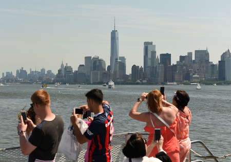 New York, USA - June 09, 2018: Passengers of the Statue of Liberty Ferry and  buildings of financial district in lower Manhattan at the background.のeditorial素材