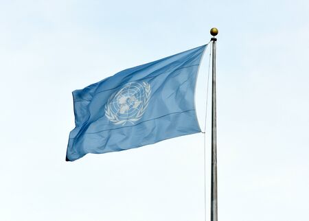 NEW YORK, USA - May 26, 2018: UN flag waving in the sky near the United Nations Building in New...