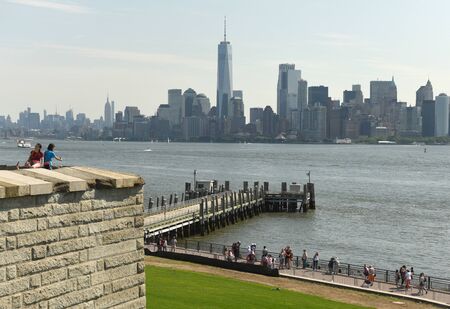 New York, USA - June 09, 2018: Tourists near the Statue of Liberty and the Lower Manhattan...