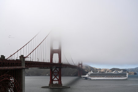 San Francisco, CA, USA - July 26, 2023: A cruise ship swims past the Golden Gate Bridge in a fog.