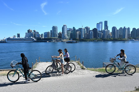 Vancouver, BC, Canada - August 16, 2023: A people on Stanley Park with downtown of the Vancouver at...