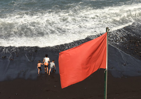 Red flag is high hazard at sea and meaning high surf and/or strong currents, so people are strongly discouraged to enter the water.の写真素材