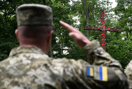 Ukrainian soldiers giving salute. The cross is decorated with red poppies in Remembrance Day. Poppy day.の写真素材