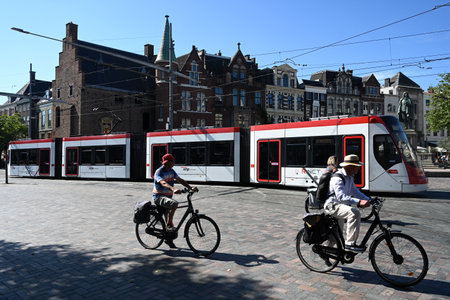 The Hague, Netherlands - August 28, 2024: A people ride bicycles near the tram in the centre of The Hagueのeditorial素材
