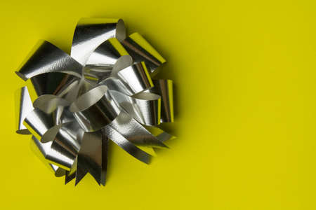 Silver gift ribbon with  paper on yellow background.