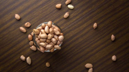 Peanuts in glass cups on wooden table background
