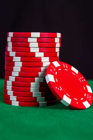 Stack of red chips on a green playing table with black backgroundの写真素材