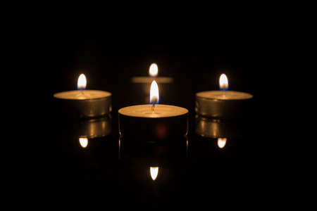 Four Tea Candles with Reflection on Black backgroundの写真素材