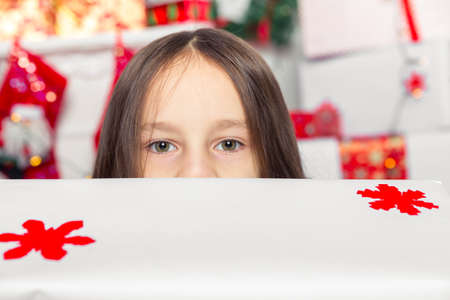 Little girl in a gray dress is holding a Christmas giftの写真素材