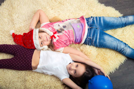 two little girls on the floor, playing at home, top view