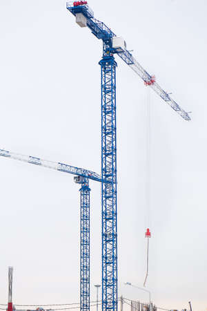 Two blue tower cranes on sky backgroundの写真素材