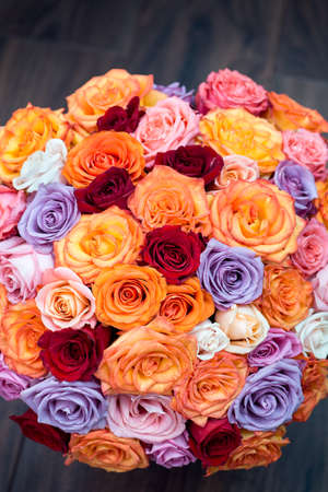 big round bouquet of colorful roses on a background of dark woodの写真素材
