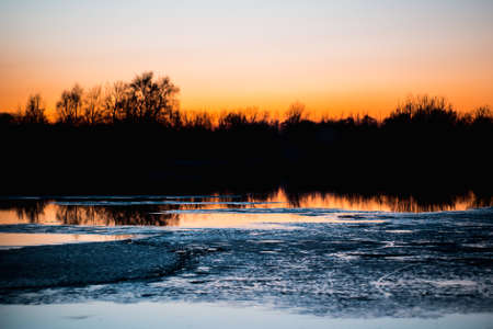 Ice on the river in the forest at sunset