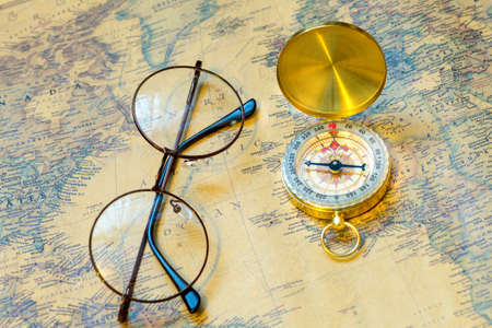 old gold compass with cover and spectacles on vintage map, macro backgroundの写真素材