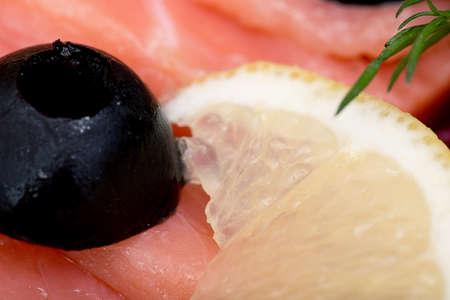 sliced red fish salmon greens lemon black olives close-up, macroの写真素材