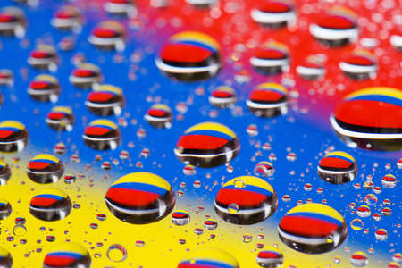 the Abstract blue-yellow-red background of water drops on glass with reflection green macroの写真素材