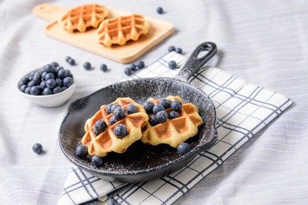 Homemade Waffles blueberries and icing on a dish that looks like a pan.の写真素材