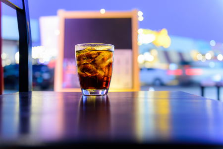 sparking water soda or cola in the glass on the table with bokeh in the night