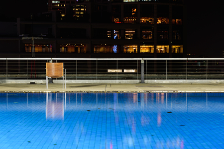 Wooden chairs are located at the hotel's swimming pool at night.の写真素材