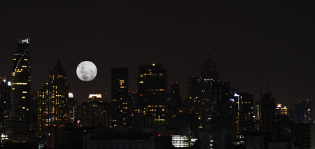 Landscape or cityscape of bangkok night view with super moon in the sky for backgroundの写真素材