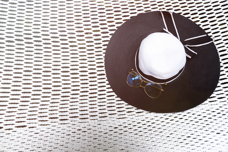 Black and white women's fashion hat with gold eyeglasses put on white hammockの写真素材