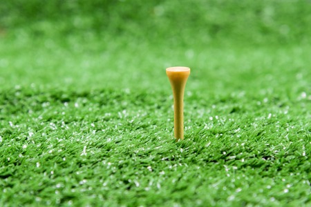 Close up of yellow wood golf tee in green grass at the golf courtの写真素材