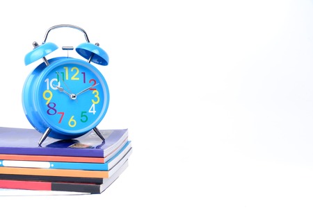 Concept Education or business :  Blue alarm clock is placed on a pile of books  isolated on white background.の写真素材