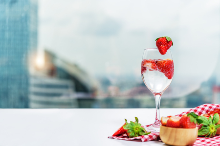 Glass of strawberry cocktail soda placed on a plaid tablecloth on white table with background of  high building and sky in bangkok Thailandの写真素材