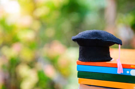 Education concept : Graduation hat or Mortarboard put on many book with background natural background.の写真素材