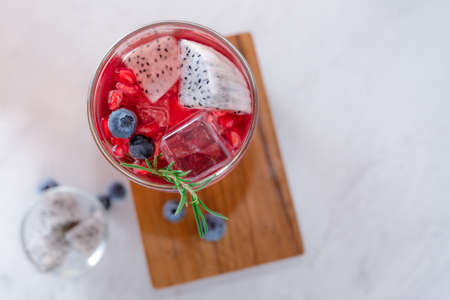 Top view of A Glass of dragon fruit juice with soda and blueberry put on wooden plate on marble tableの写真素材