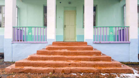 The main entrance to the building. Concrete brown staircase. Multi-colored wooden fenceの写真素材
