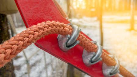 Close up of red rope and metal clips used for suspension bridge to the rope Park.