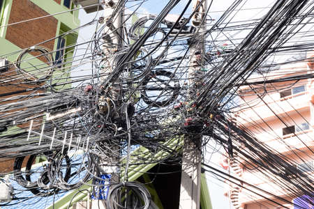 Messy wires attached to the electric mast. The chaos of cables and wires on an electric pole. Many...