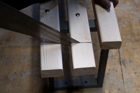 Sawing or cutting a wooden board or bar with a hand saw or hacksaw during carpentry or carpentry...