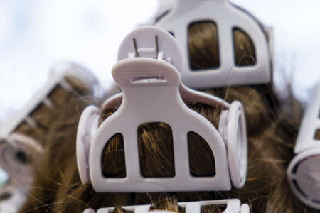 Curling rollers in a woman's hair. Hair curlers on the girl's head close up.の写真素材
