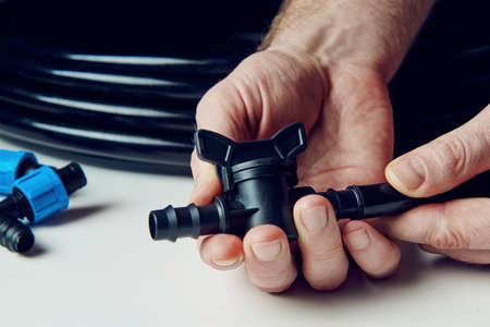 Preparing for planting in early spring. Male hands in the frame hold a faucet for drip irrigation....