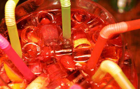 Summer, cold drink with ice, fruits and straws, close-up, soft focus. Sangria in a large container...