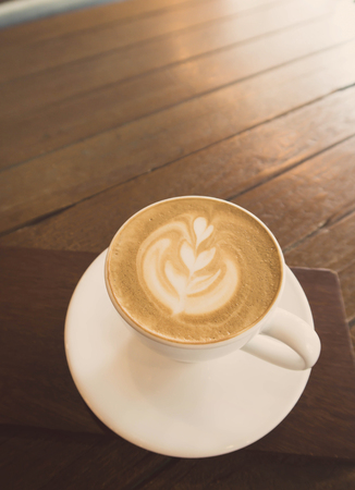 A cup of cappuccino coffee on wooden table in coffee shop background with vintage filterの写真素材