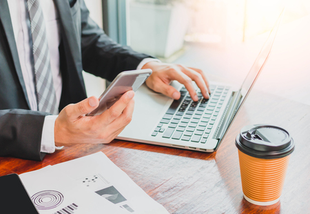 Businessman working with laptop and smartphone on wooden tableの写真素材