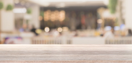 Wood table top and blurred bokeh cafe and coffee shop interior background with vintage filter - can...
