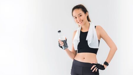 Asian beautiful women holding water bottle after play yoga and exercise on white wall background...