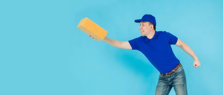 Asian happy delivery man wearing a blue shirt running and carrying paper parcel boxes isolated on on...