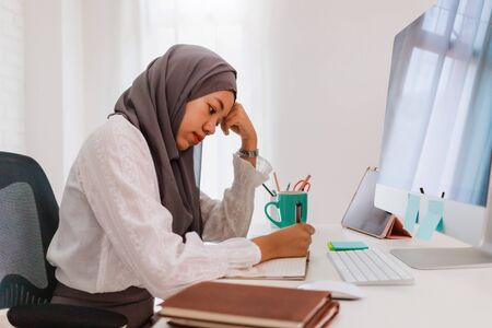 Asian muslim woman student or businesswoman wearing hijab.Working from home with computer on table.Concept of social distancing working alone at home in the epidemic situation of covid-19.の写真素材