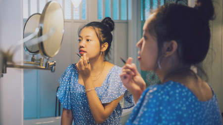 Asian beautiful woman make up cosmetic on mirror in bathroom at hotel interior background.の写真素材