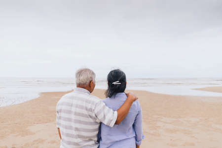Asian old senior couples walking at the beach by the sea background on weekend vacation.Concept of happy living for the elderly.の写真素材