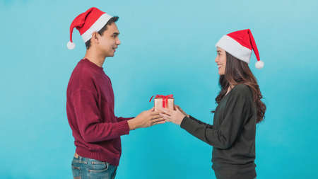 Happy young Asian couple holding Christmas gift boxes with happy smiling face isolated on blue background in studio shot.Christmas celebration of lover concept.の写真素材